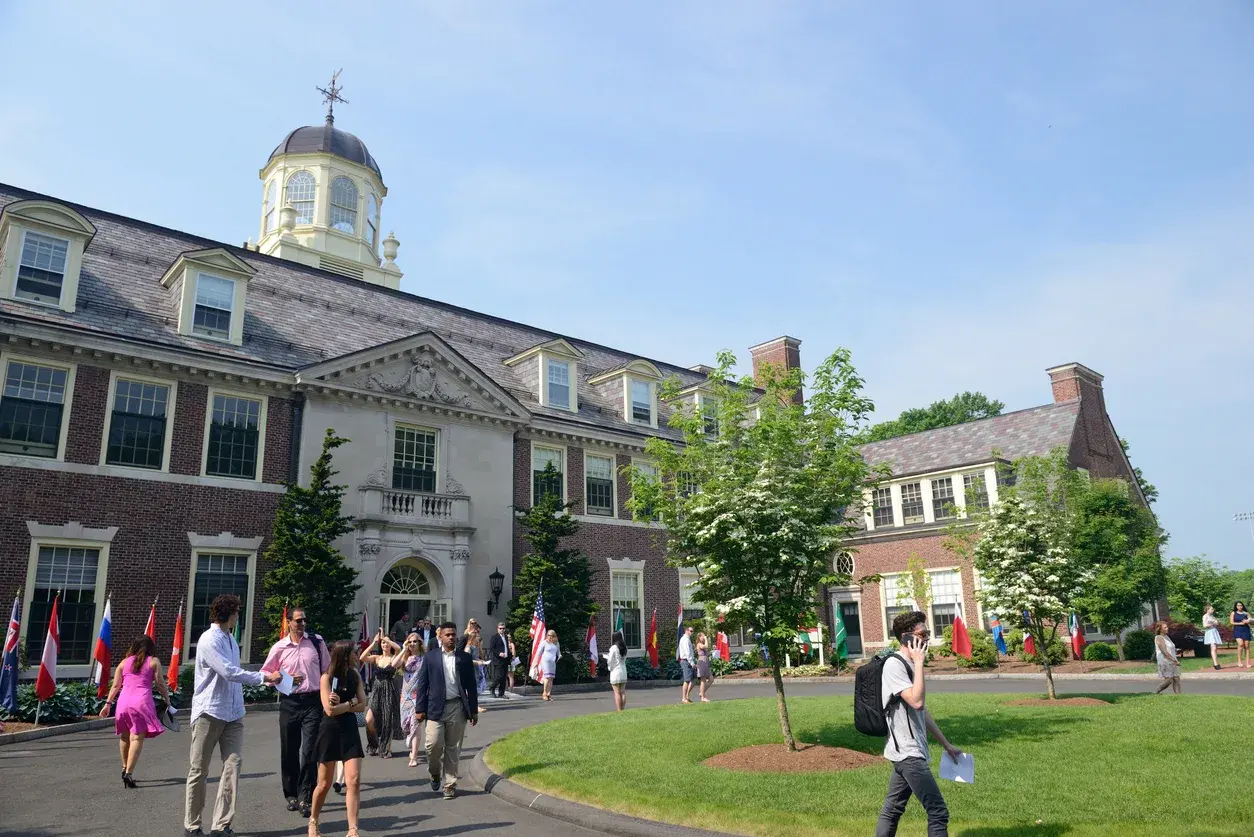 A boarding school campus building with international flags and students arriving