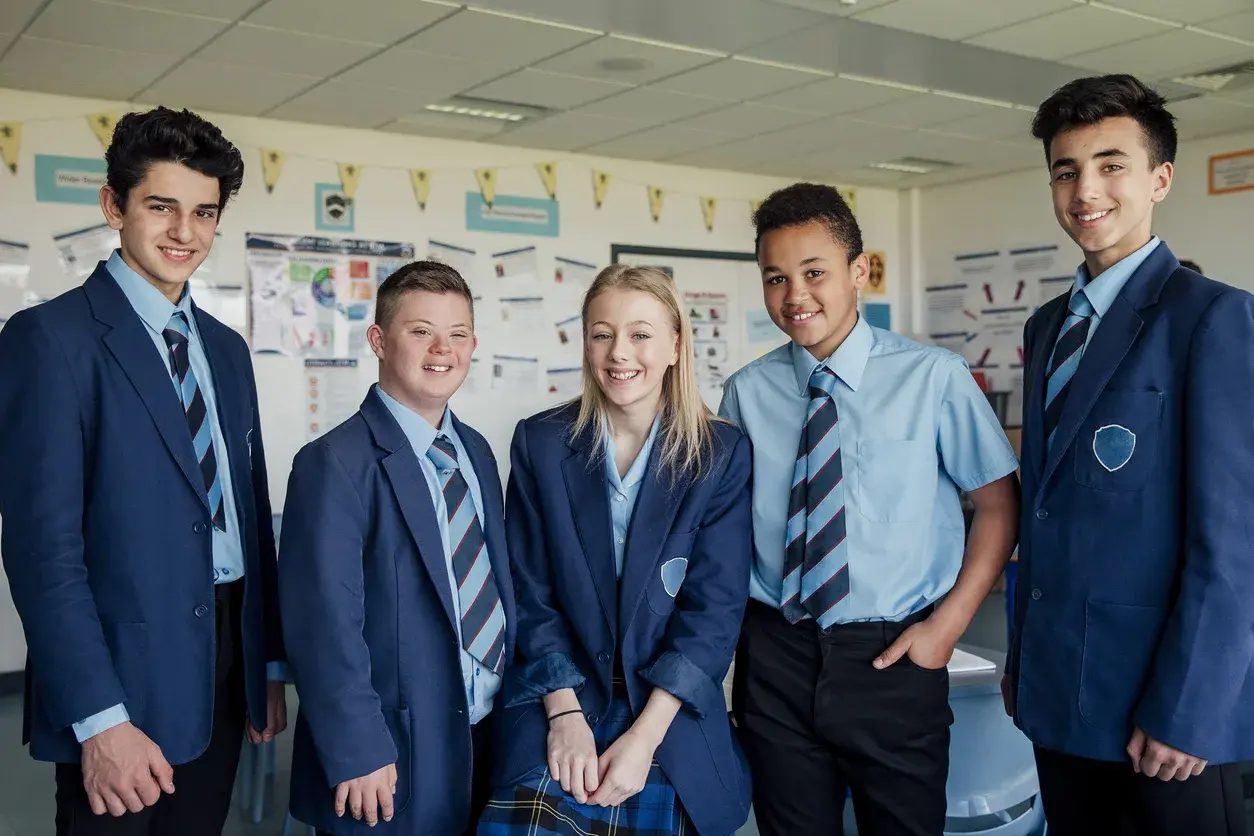Smiling secondary school students sitting together in class